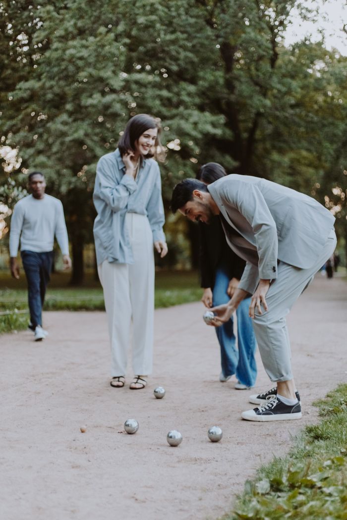Friends enjoy a game of boules in a serene green park, having fun and socializing outdoors.
