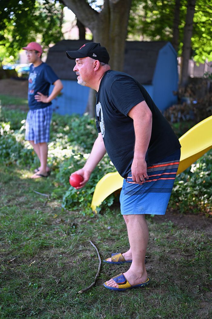 Two men enjoying a game of bocce in a sunny backyard setting.