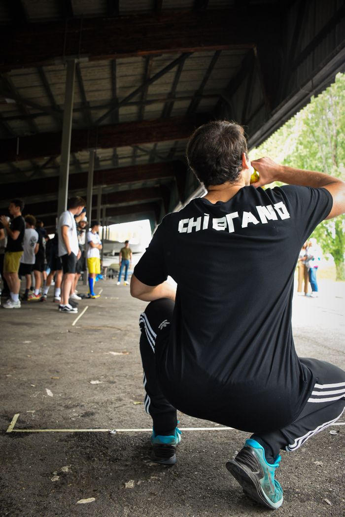 A man drinking and taking a break during an outdoor athletic event, showcasing teamwork and endurance.